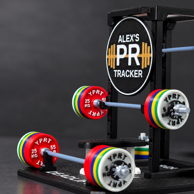 A custom-built black metal weight rack labeled 'ALEX'S PR TRACKER' holding three barbell stacks with colorful weight plates. The plates feature red, white, green, yellow, and blue accents, with some plates showing 'YPRT' branding.