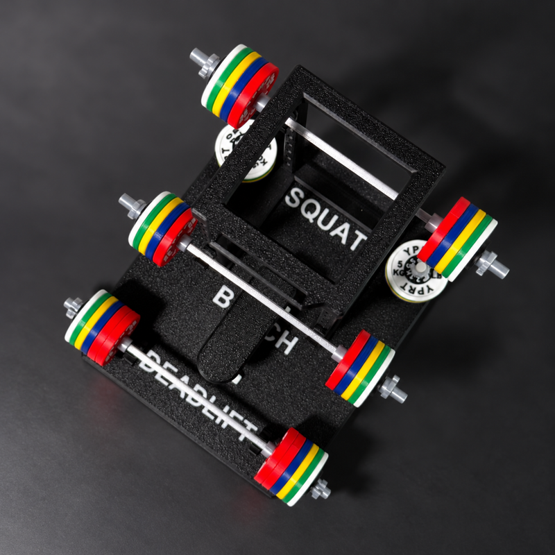 A black foam weightlifting platform with two barbell setups, each loaded with colorful weight plates in red, green, yellow, and blue. The platform has white text reading 'SQUAT' and 'BENCH', and a circular dial marked 'SQUAT 180 LB'.